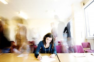 Girl concentrating on writing in blurred room