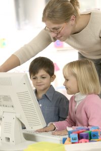 Adult helping children on computer